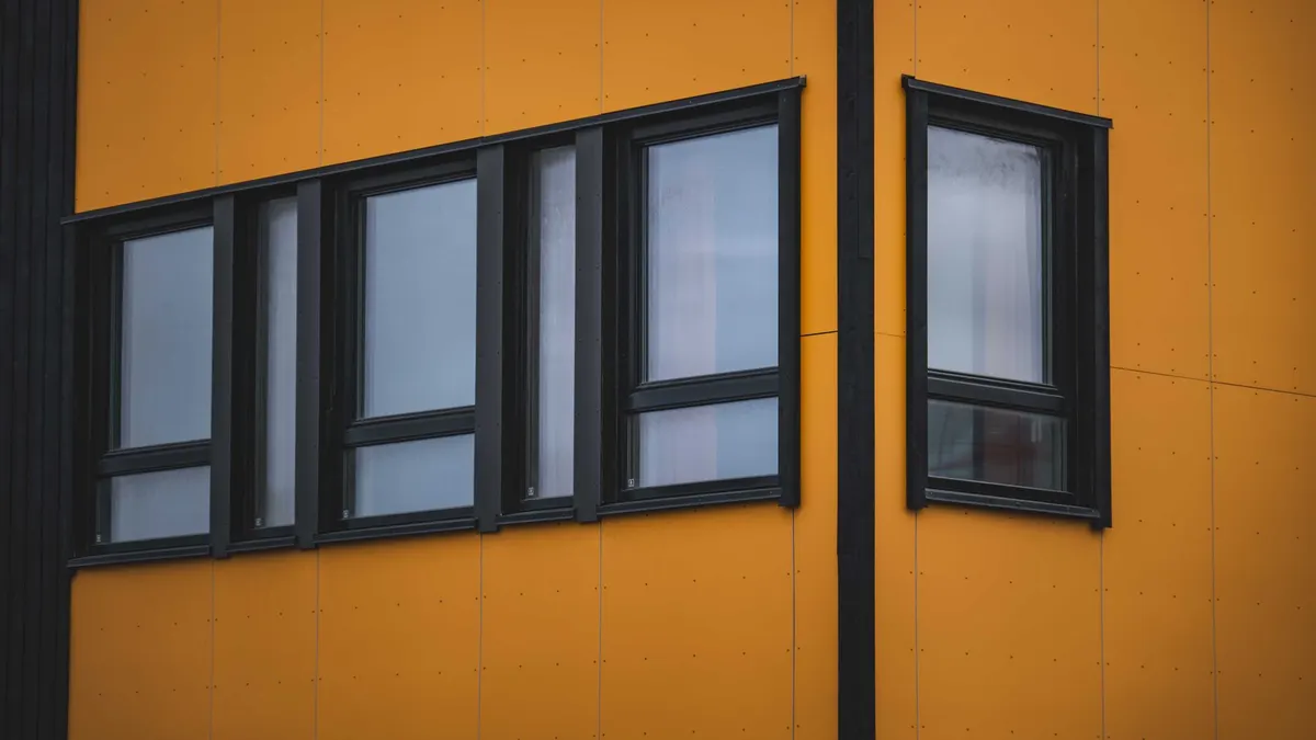 Architectural detail of a modern building facade with a vibrant yellow exterior and multiple windows.