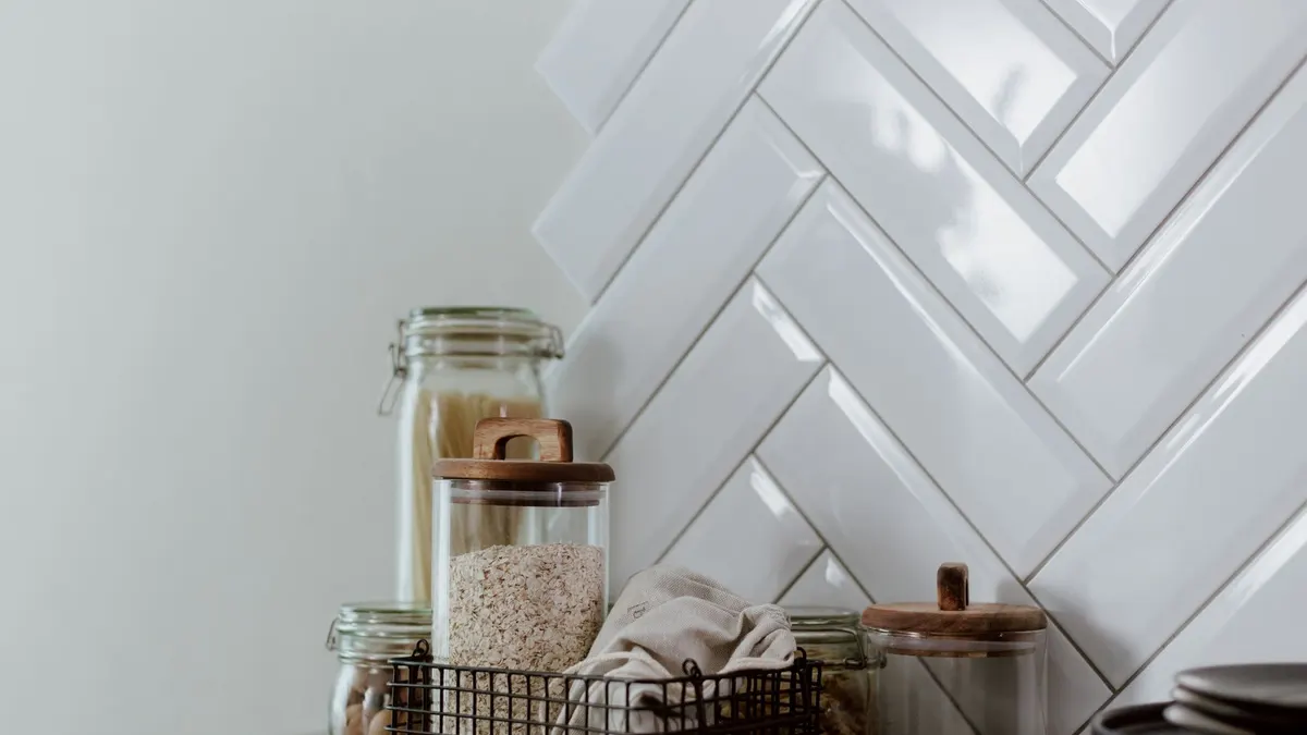 Stylish kitchen setup featuring glass jars with pasta and grains on a clean counter.