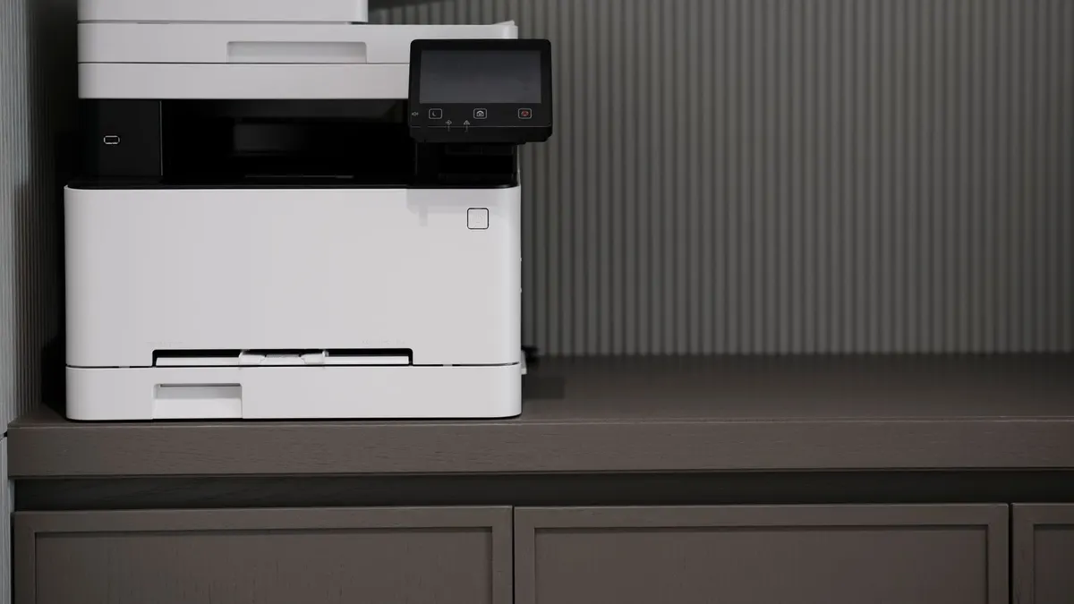 A sleek, modern printer situated on a minimalist office desk with a textured background.