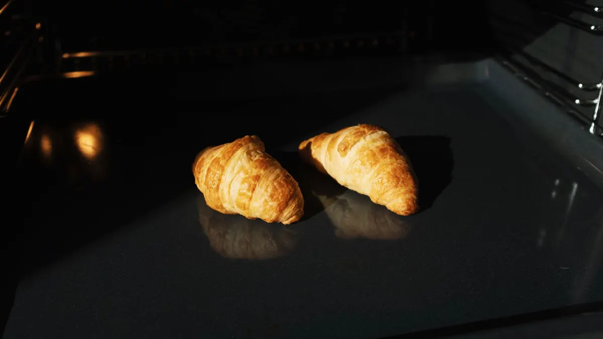 Freshly baked croissants in an oven, showcasing their golden texture and delicious appeal.