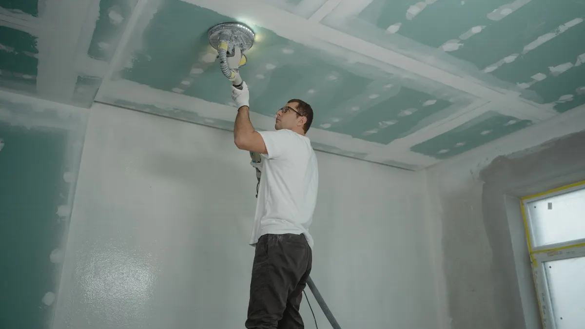 A worker expertly polishes a ceiling indoors, demonstrating home renovation skills.