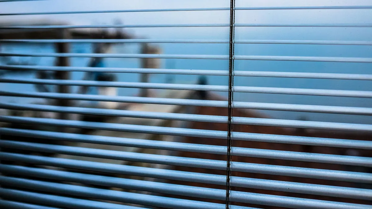 Blurred outdoor scene visible through modern window blinds, creating a tranquil ambiance.