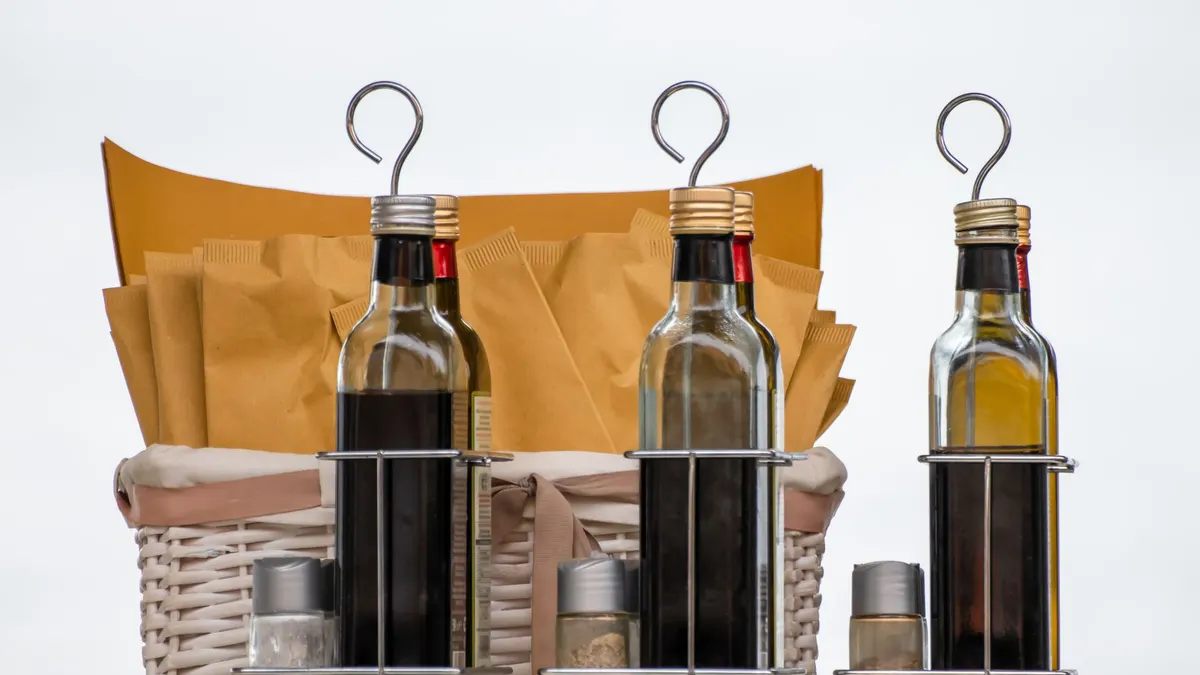 A collection of glass bottles with condiments and spices in a wicker basket.