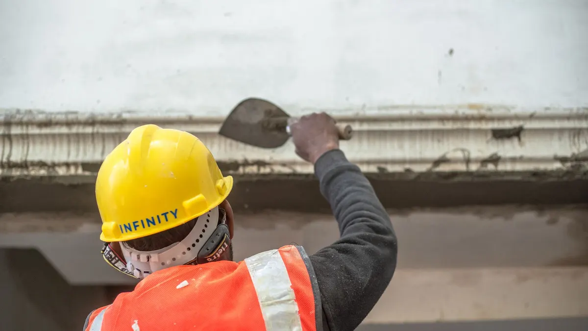 A construction worker in safety gear renovating an interior wall in Delhi, India.