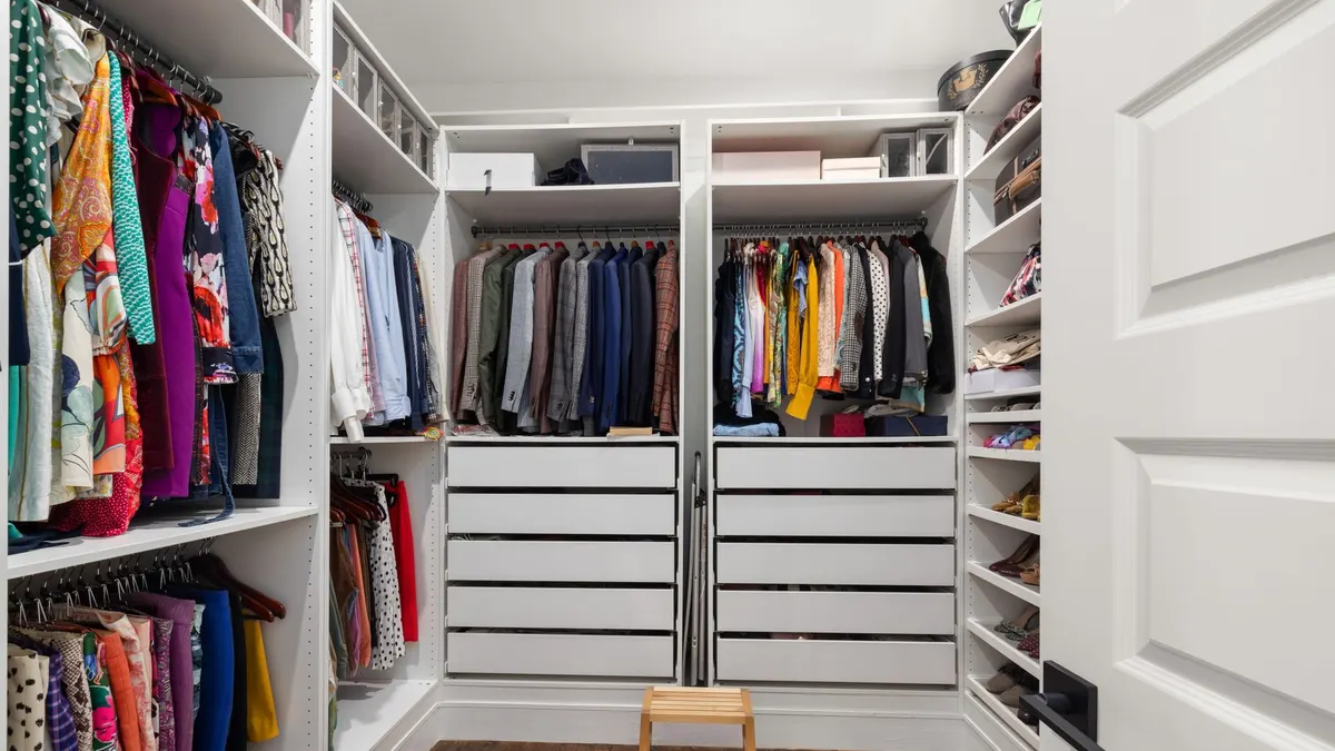 A neatly arranged walk-in closet showcasing a colorful variety of clothes and shoes.