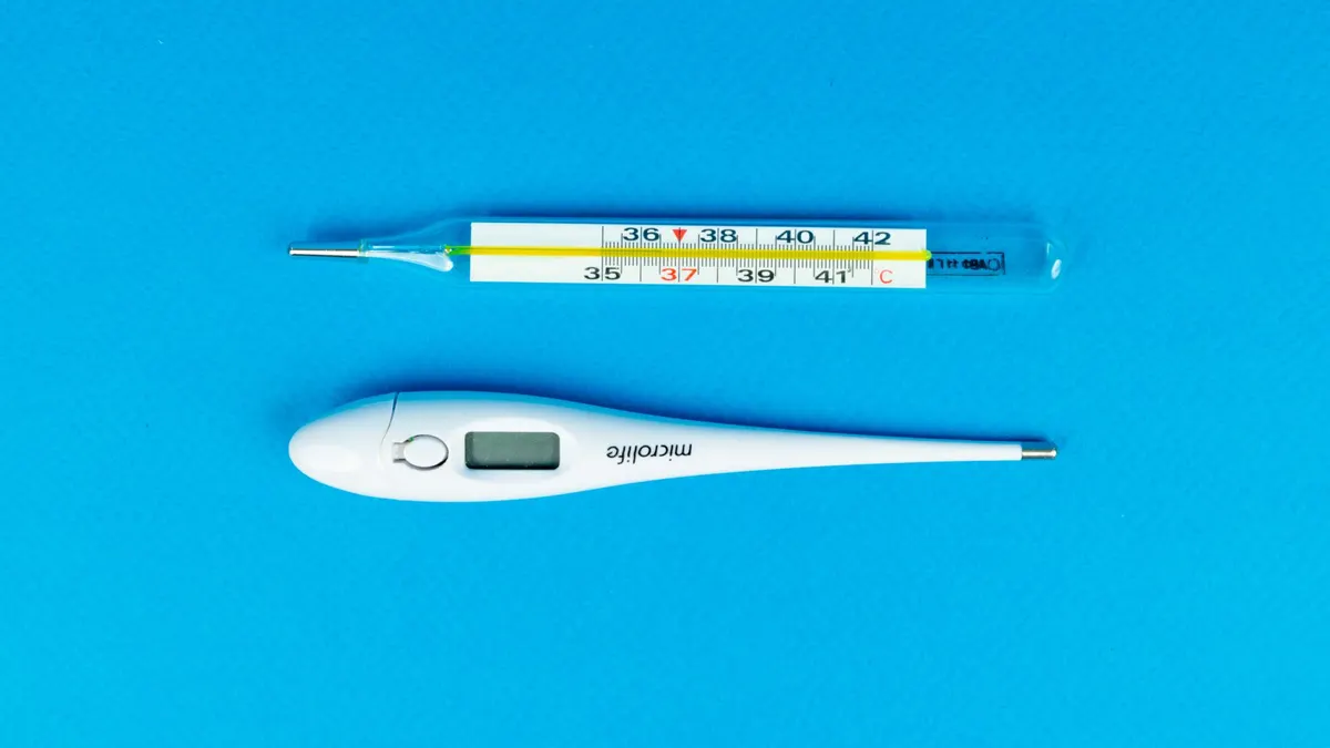 Digital and mercury thermometers on blue background for medical concept.