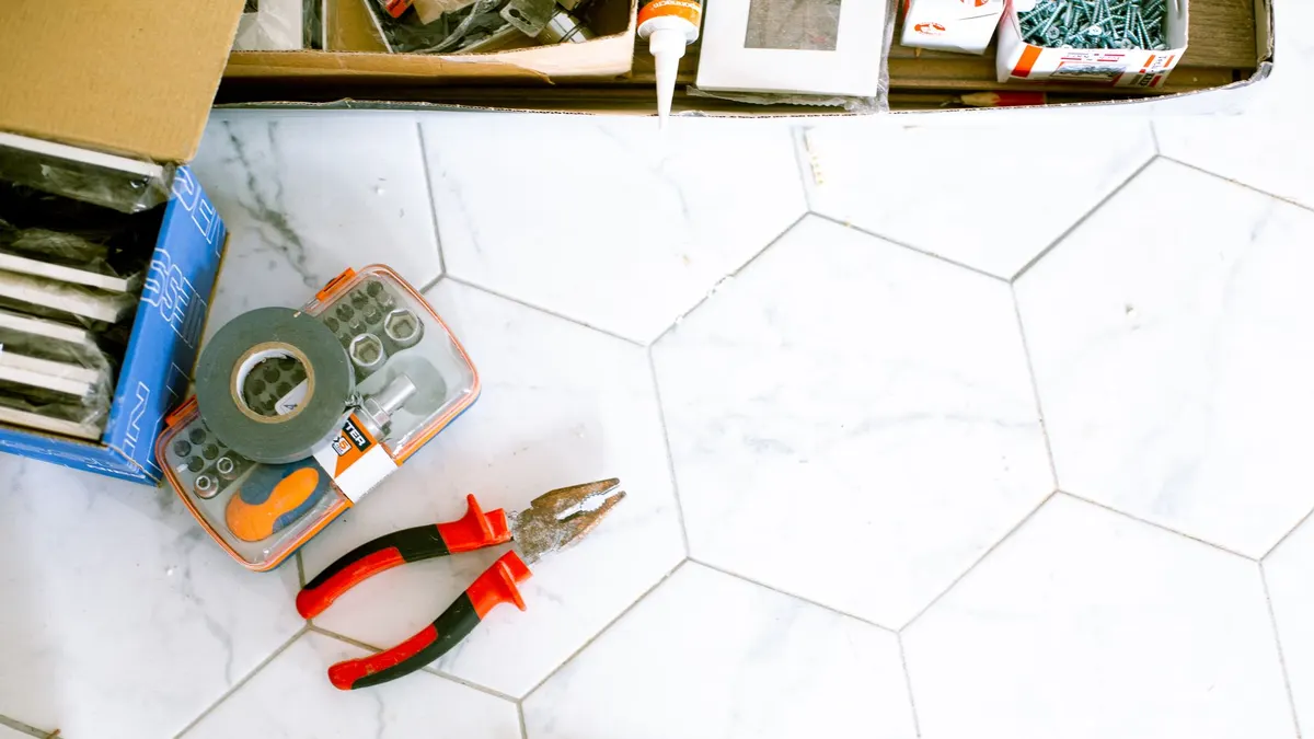 A selection of home renovation tools placed on a white tiled floor, ready for use.