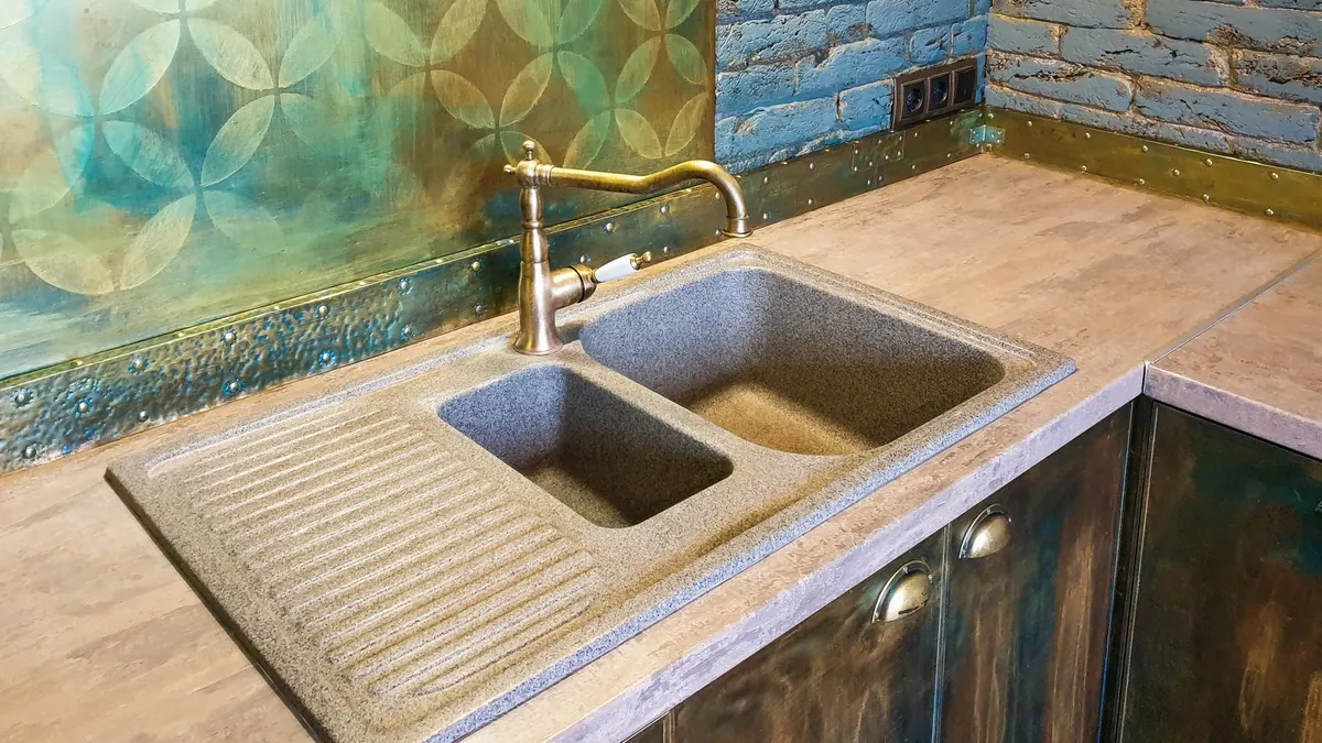 Cozy kitchen interior featuring a rustic double sink, decorative brick wall, and vibrant backsplash.