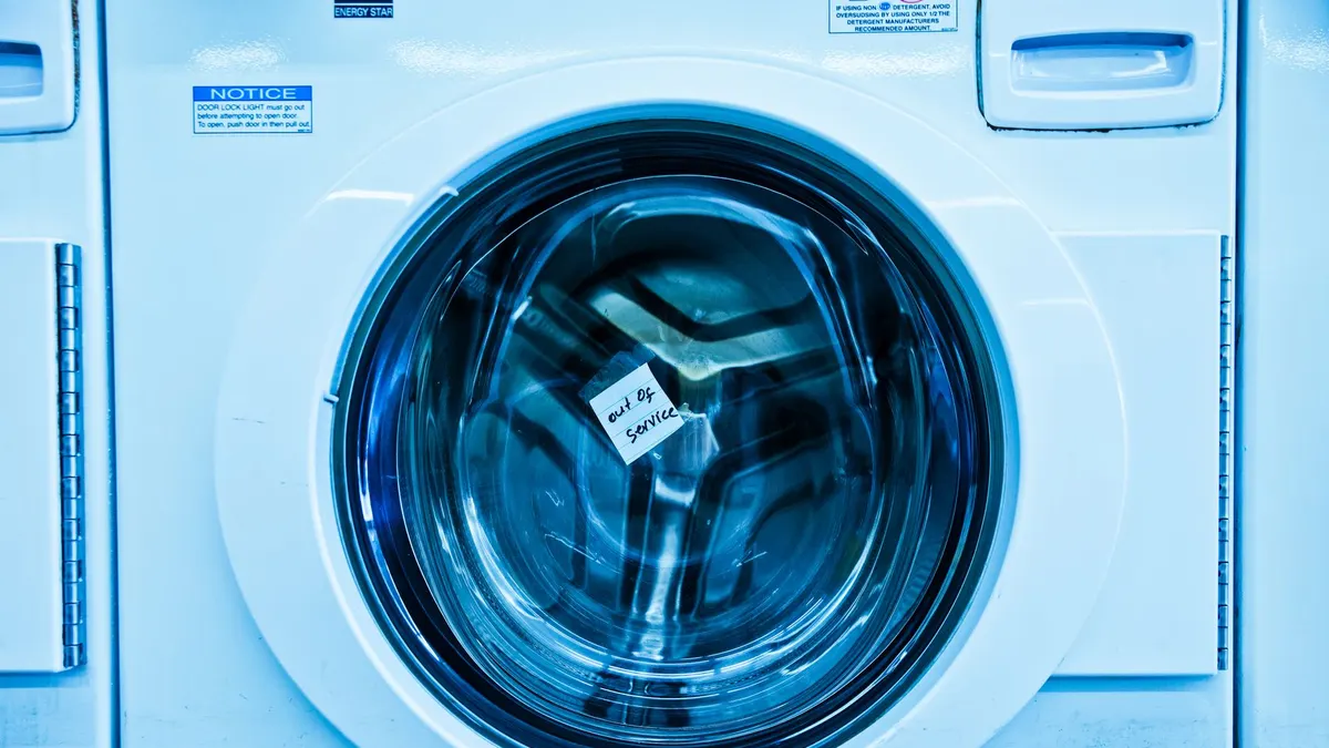 Close-up of an out-of-service washing machine in a laundromat with a blue tint.
