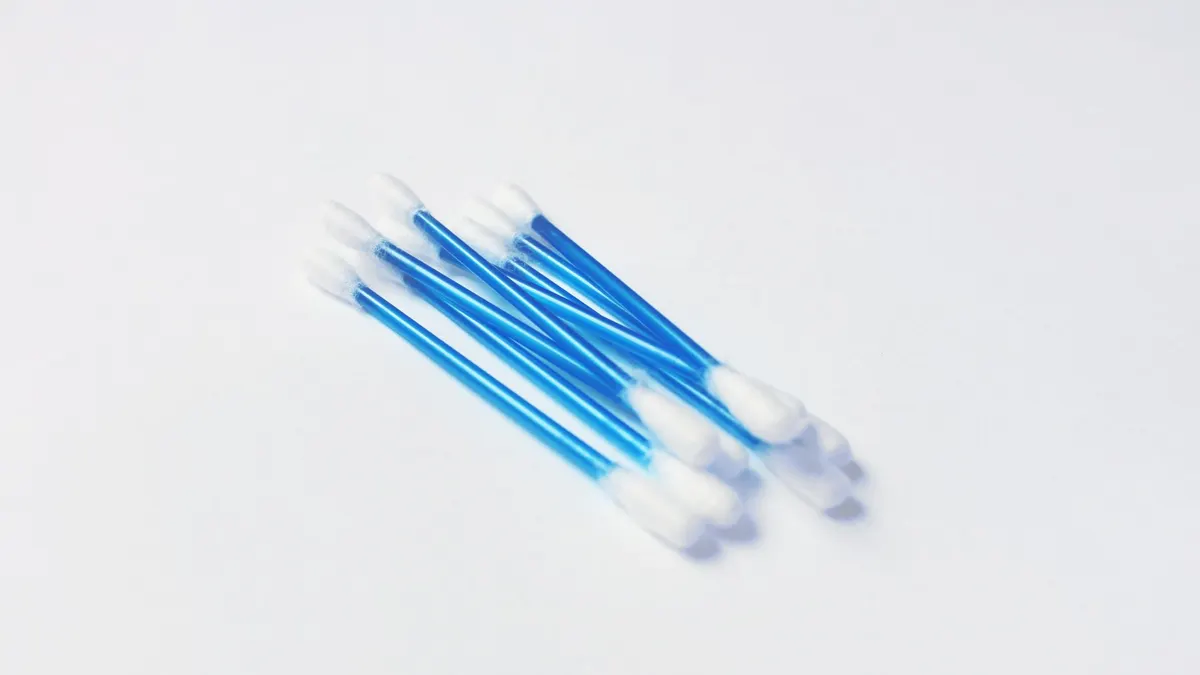 A minimalistic close-up image of blue handled cotton swabs on a white surface.