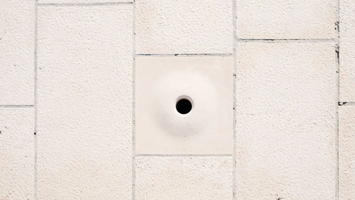 Close-up of a minimalist white brick wall featuring a central circular hole.