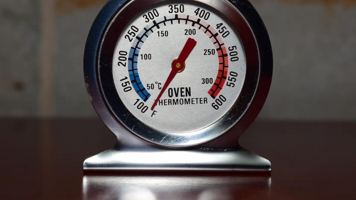 Close-up of a metallic oven thermometer showing temperature in Celsius and Fahrenheit.