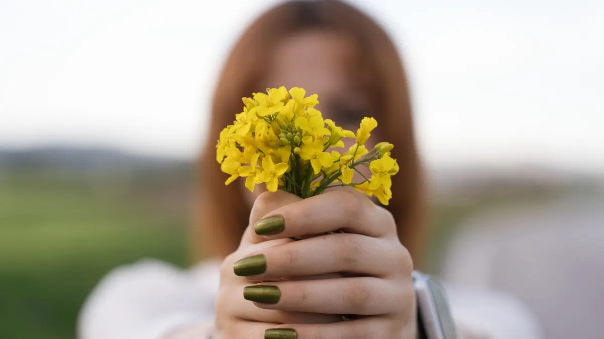 Close-up of a woman holding yellow flowers with green nails in Merzifon, Türkiye.