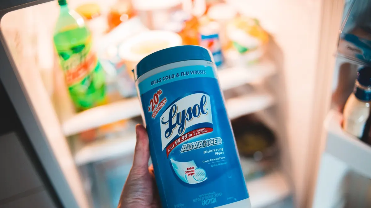 High angle of crop faceless person holding container of antibacterial wipes near opened fridge during housework