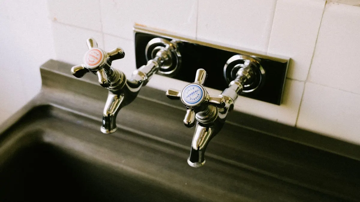 Detailed view of chrome sink faucets with classic hot and cold labels in a kitchen setting.