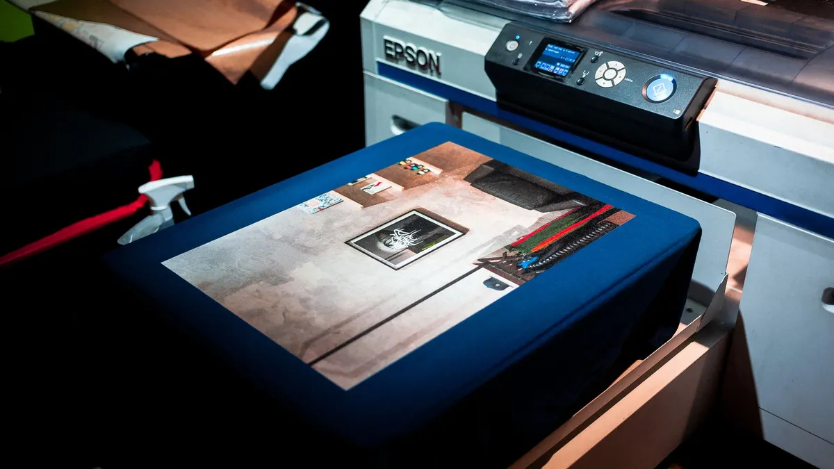 Close-up of a professional printer printing a custom artwork design on fabric in a studio setting.