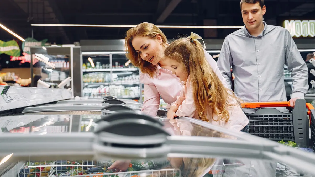 A happy family shopping in the supermarket's freezer section, emphasizing togetherness and love.