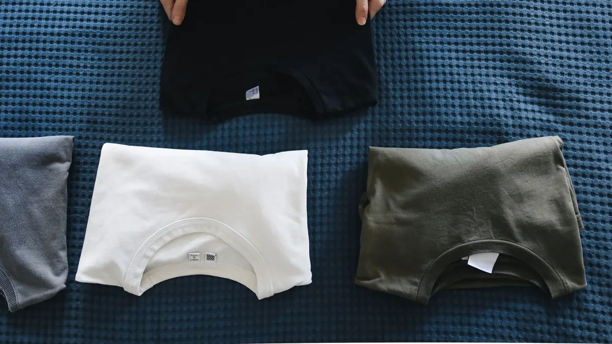 Top view of neatly folded colored T-shirts laid out on a blue bedspread, perfect for housekeeping themes.