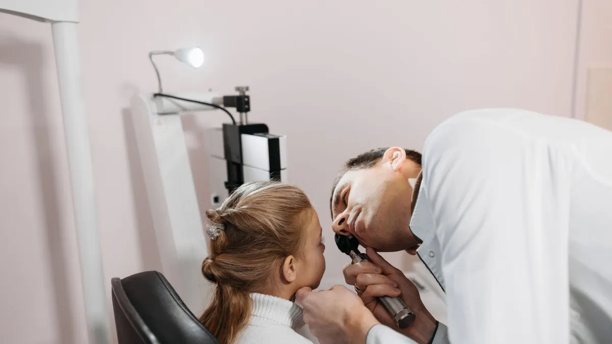 A doctor examines a young girl's ear during a medical appointment in a clinic.