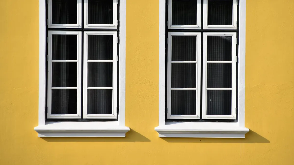 Two white-framed windows on a vibrant yellow building facade in Büsum, Germany.
