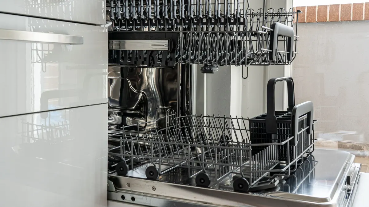 Open and empty dishwasher in a sunlit modern kitchen ready for use.