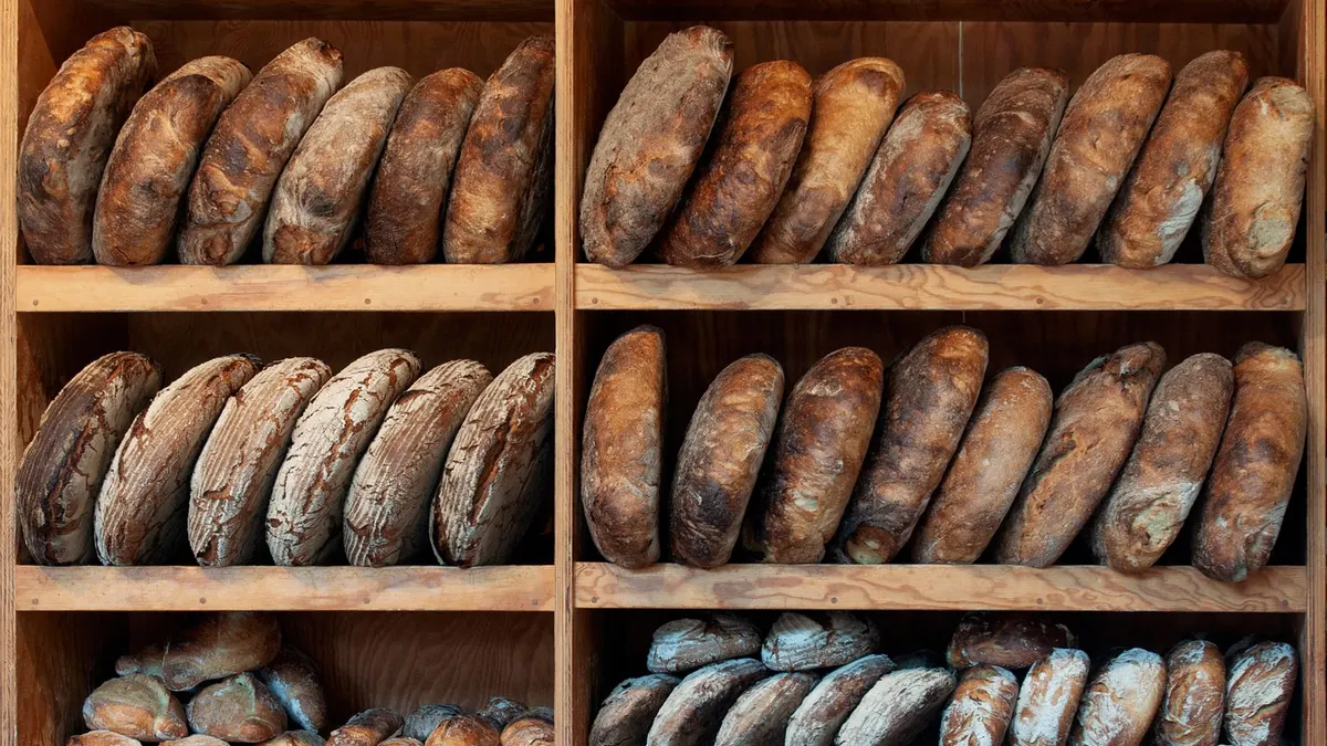 A variety of artisanal breads neatly arranged on wooden shelves, creating a rustic display.