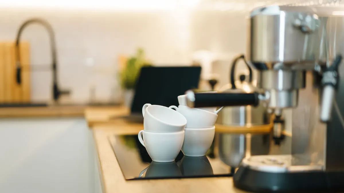 A modern espresso machine with coffee cups on a kitchen counter, showcasing a cozy and inviting setup.