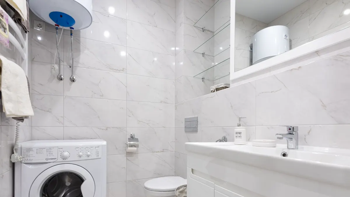Bright minimalist bathroom featuring a washing machine and modern fixtures.