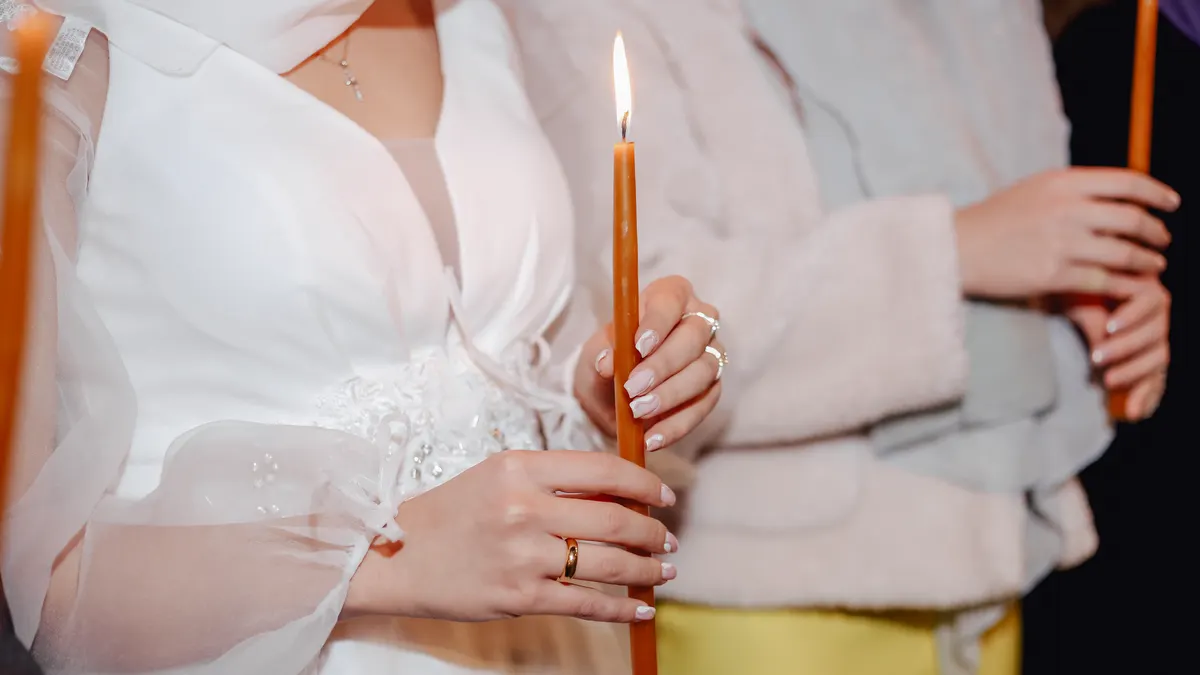 Close-up of a bride holding a lit candle during a wedding ceremony, symbolizing unity and love.