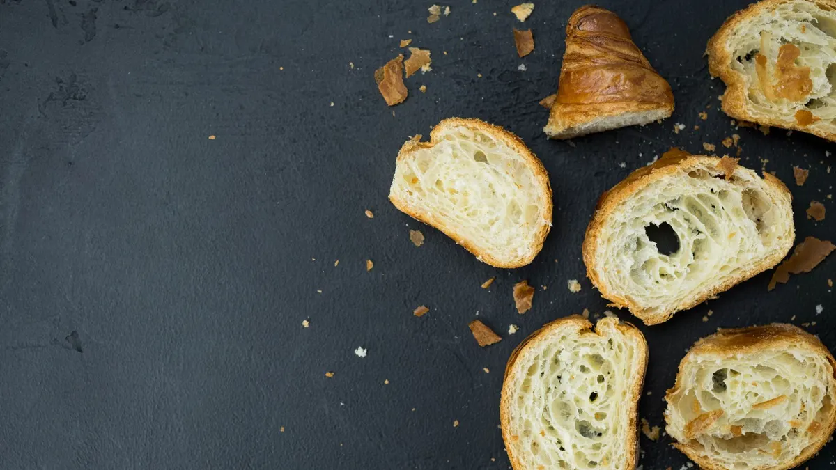 Sliced croissants on a black surface with crumbs. Perfect for food photography enthusiasts.