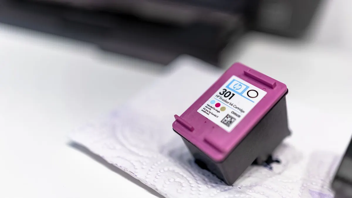 A close-up of a printer ink cartridge resting on a paper towel, showcasing its design and details.