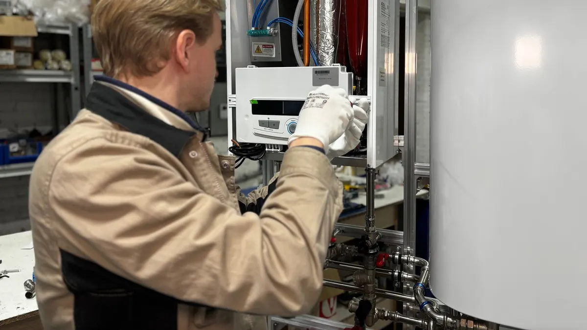 Technician installing or repairing a heating system in an indoor workshop setting.