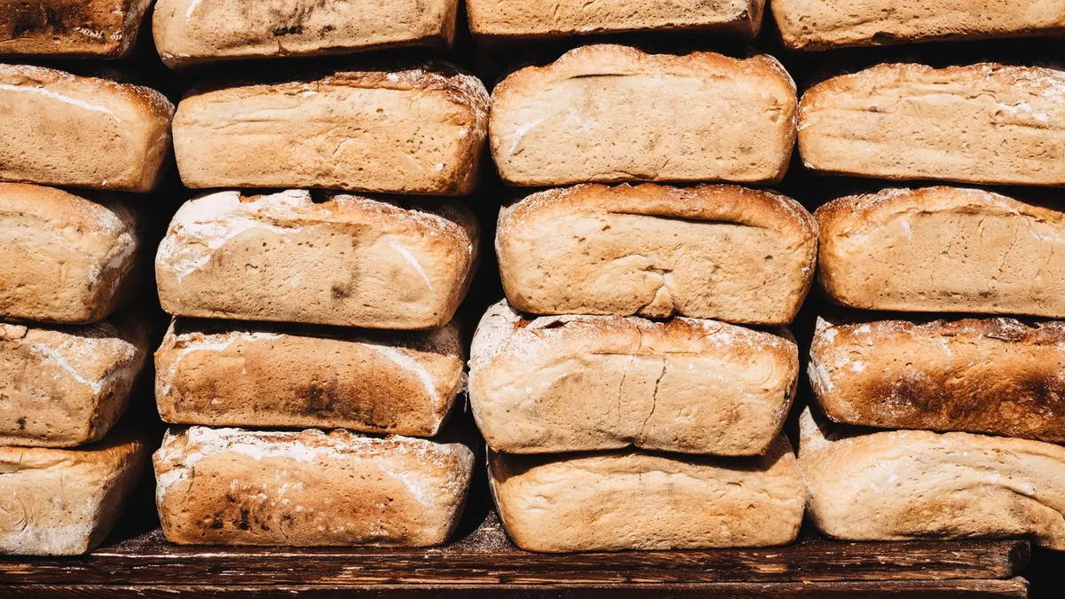 A stack of freshly baked rustic bread loaves on a wooden board. Perfect for bakery promotions.