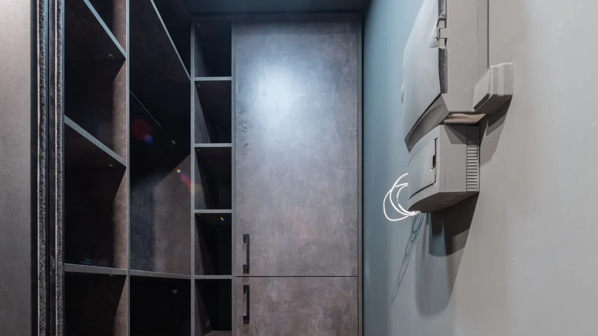 Spacious modern walk-in closet with shelves and leather boots on the floor.