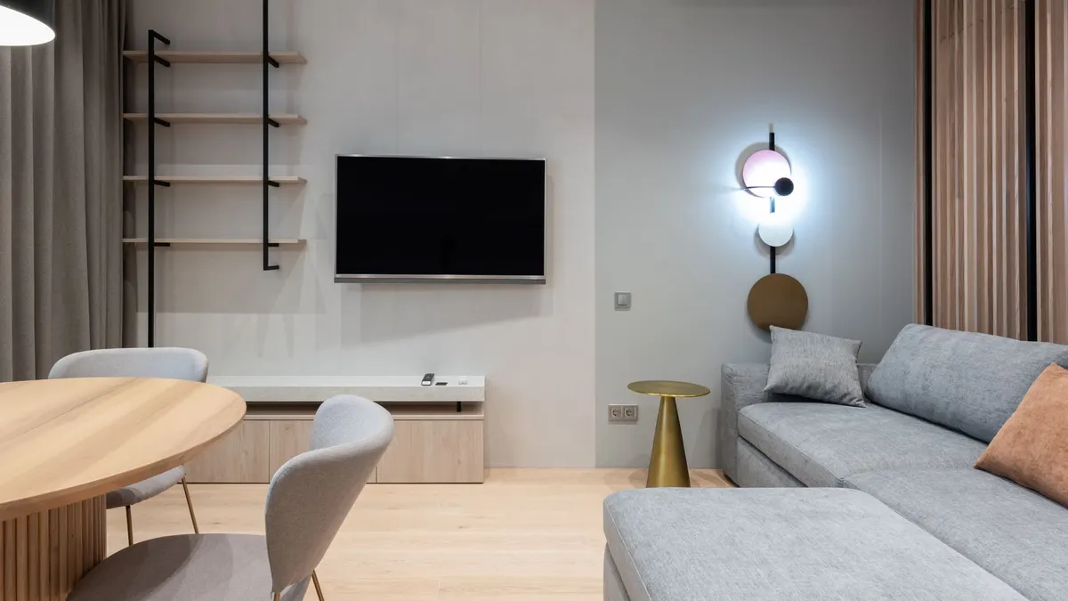 Comfortable living room furnished with big sofa placed near TV and shelf with curtains