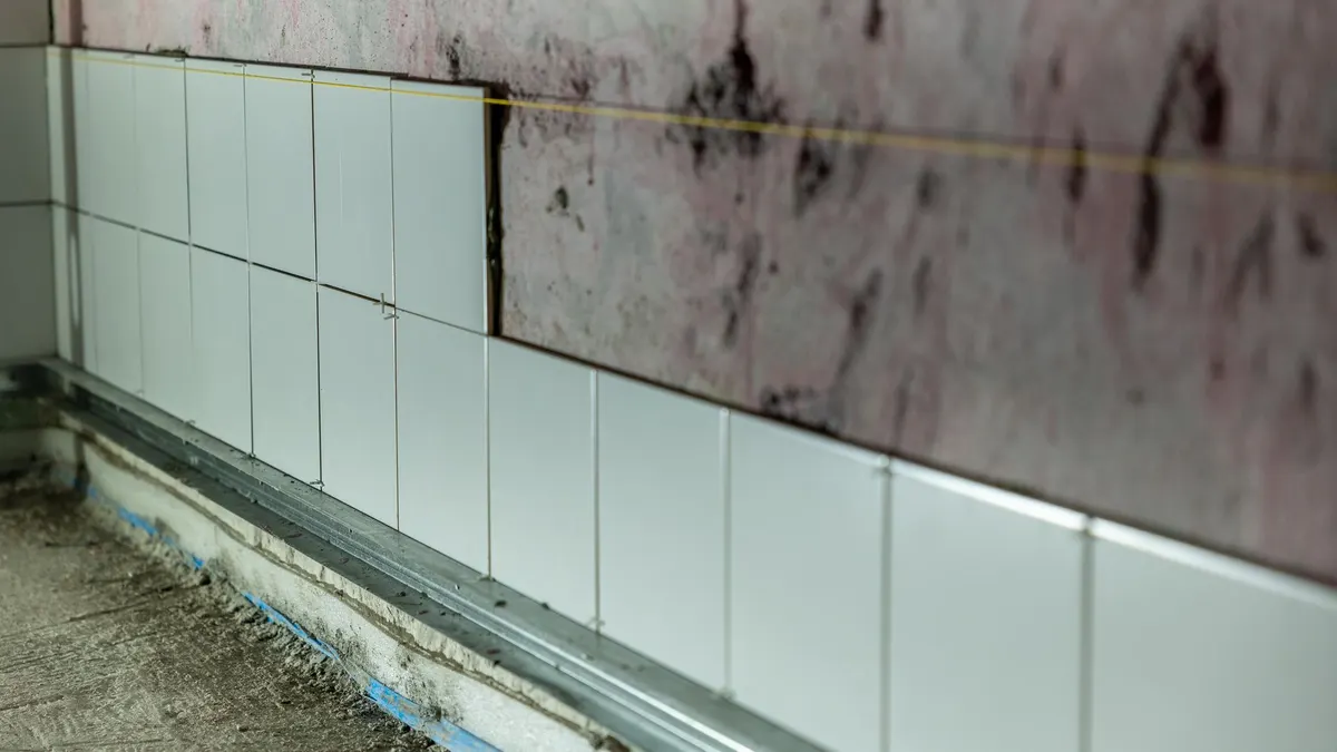 Close-up of partially tiled wall in a construction area, showcasing incomplete renovation work.